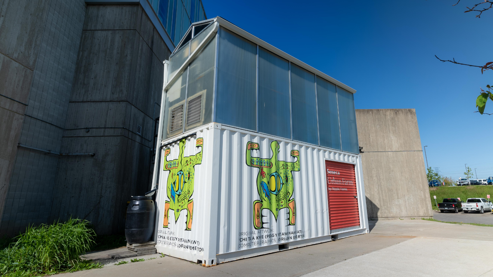 Exterior of a modular indoor farm container installed on a paved lot beside a building